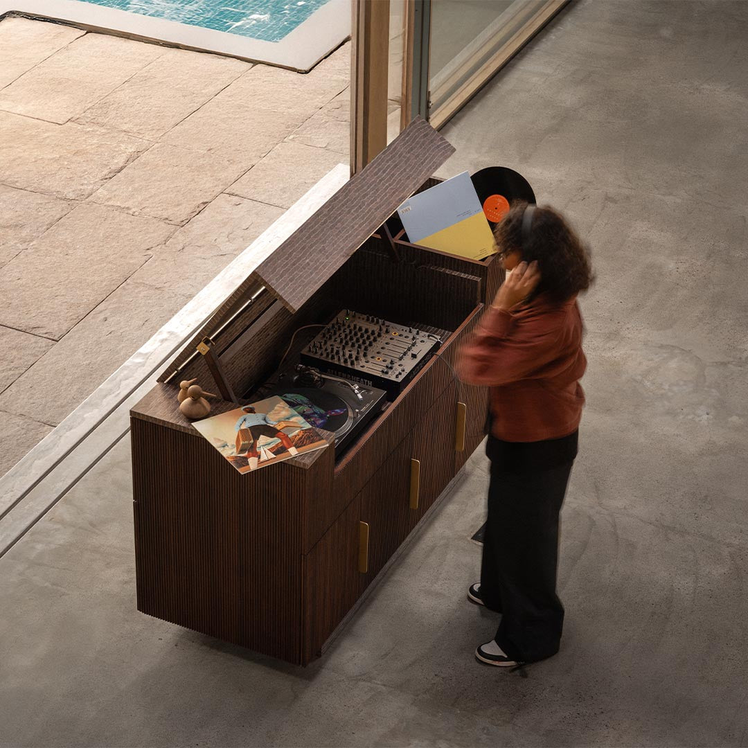A serene moment as a girl enjoys music from the Record Console, a vintage-inspired media unit from the Magari x AAD Collection, designed for audiophiles.