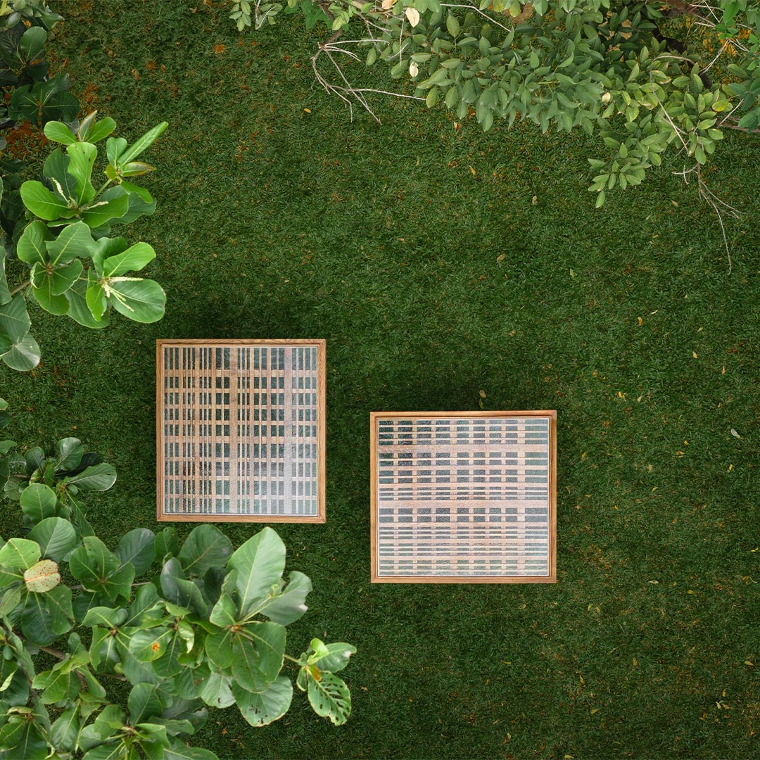 A top view of two Ibbani Side Tables from the Magari x AAD Collection, showcasing a slatted wood base topped with fused glass, creating a sculptural contrast.