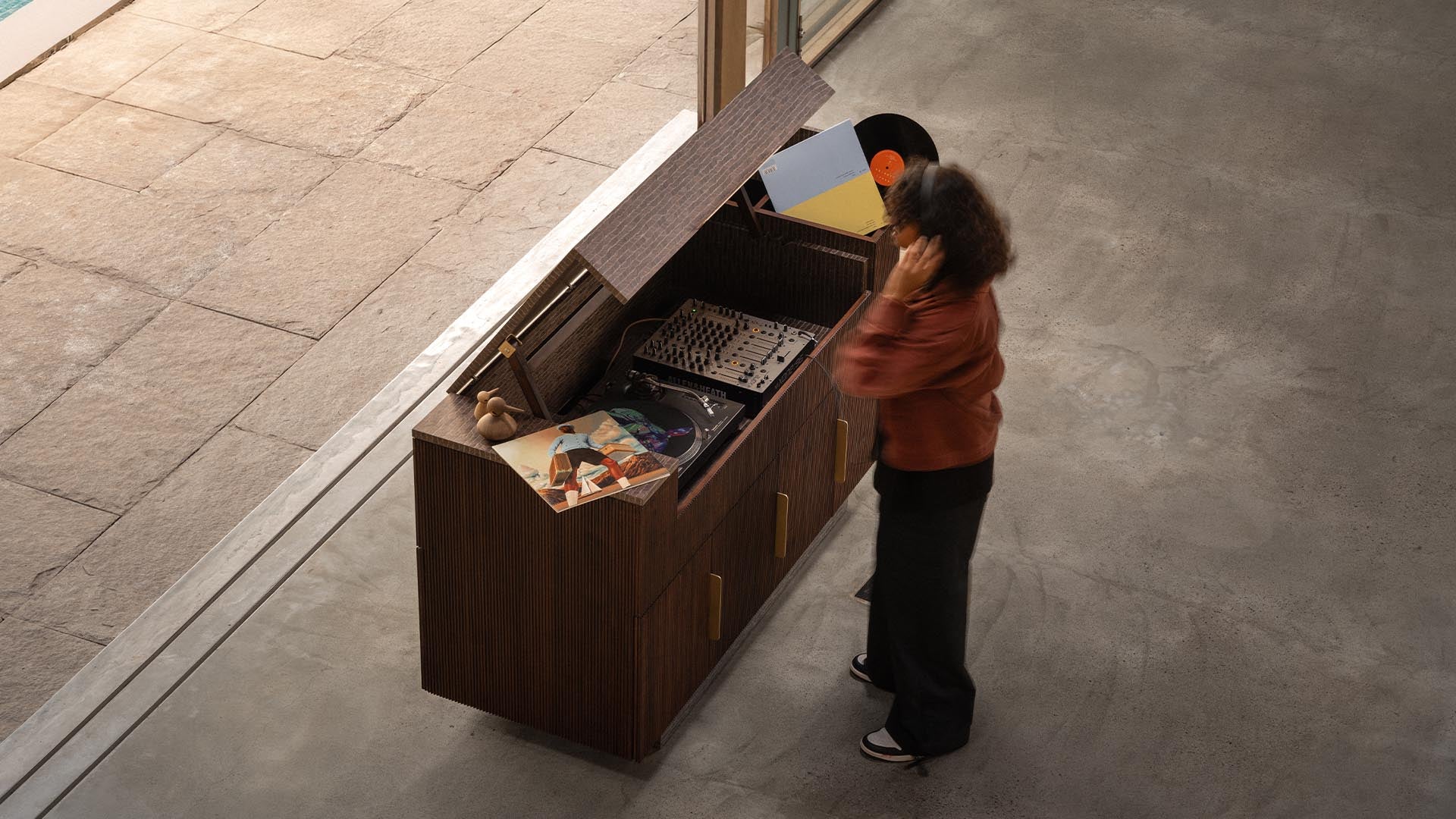 A serene moment as a girl enjoys music from the Record Console, a vintage-inspired media unit from the Magari x AAD Collection, designed for audiophiles.